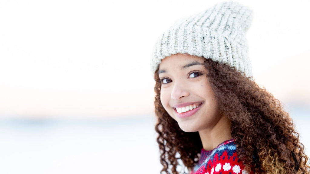 woman with curly hair and hat, snow background