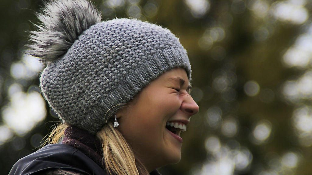 woman with blonde hair laughing wearing hat