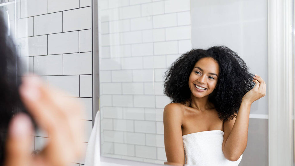 woman with curly hair looking in mirror