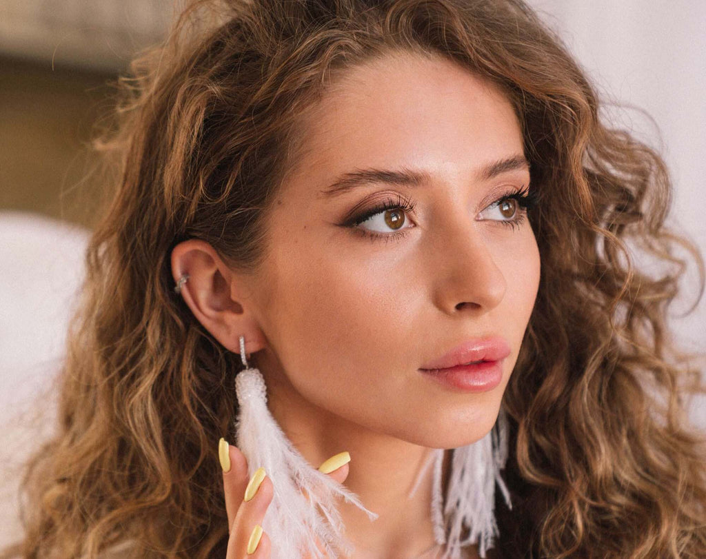 woman feather earrings curly brunette hair