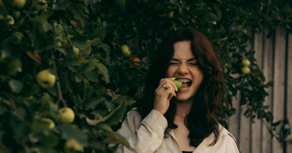 brunette eating fruit next to tree