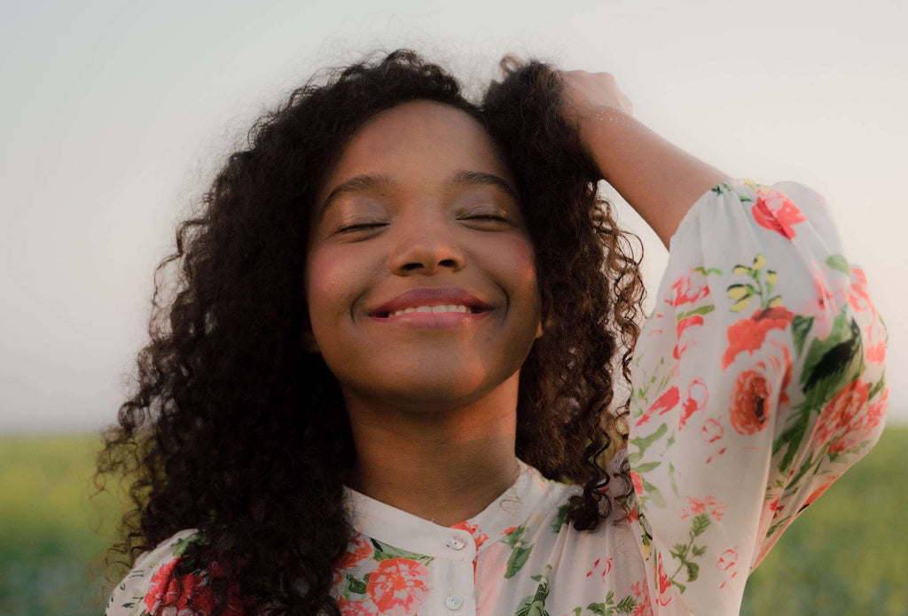 woman curly hair smiling outside