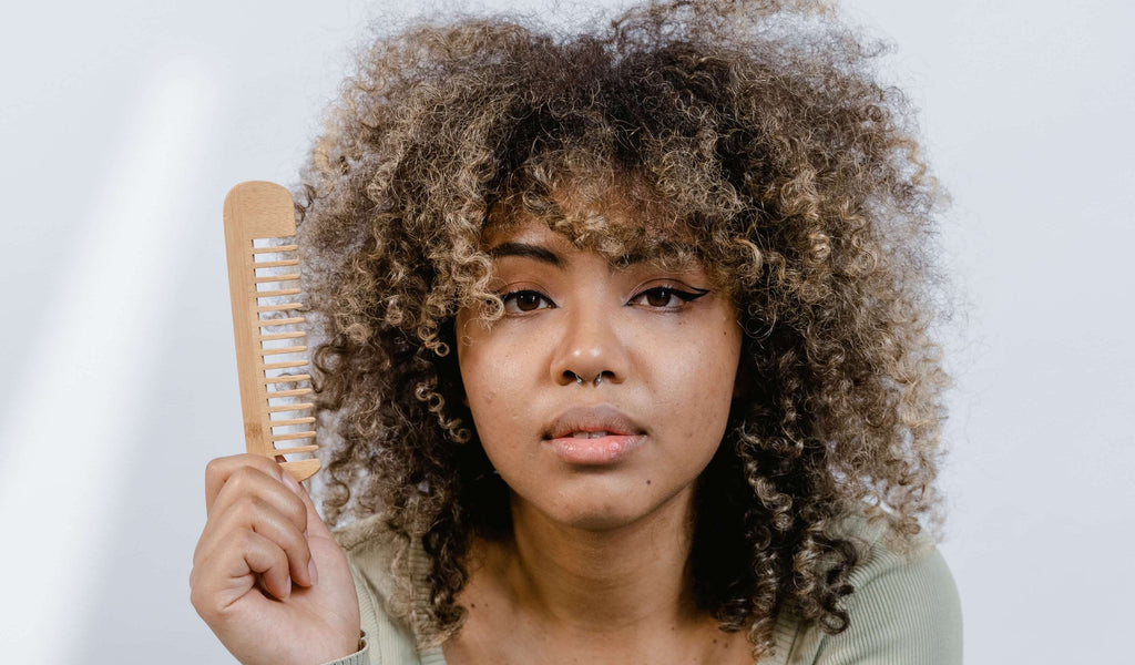 woman holding comb kinky brunette hair