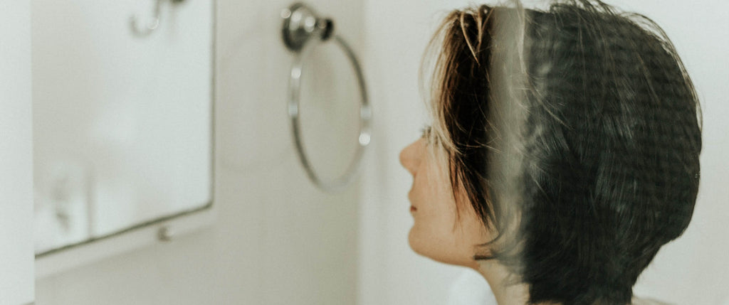 woman short hair looking in mirror